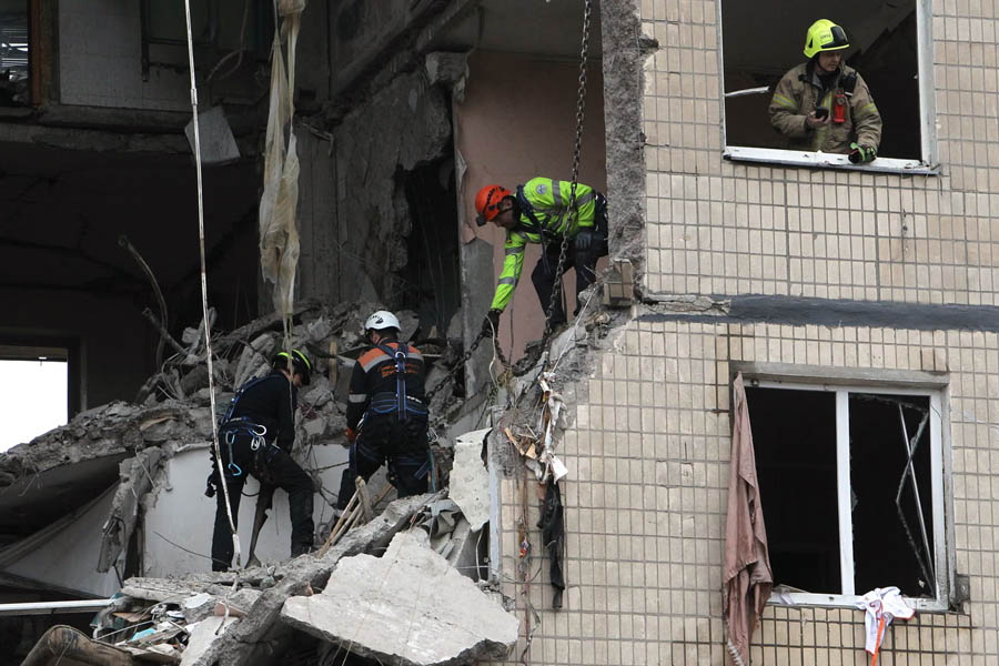 Ukrainian rescuers working amid rubble at a Dnipro apartment building destroyed by a Russian drone attack.