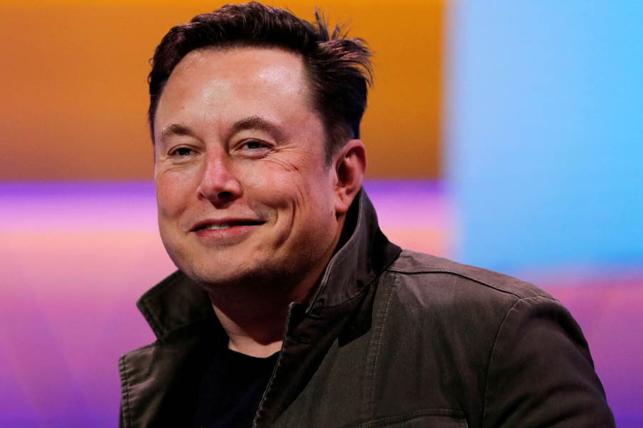 Elon Musk smiling in front of a Tesla vehicle, illustrating his potential to increase his stake in Tesla to 25% under the new pay package.