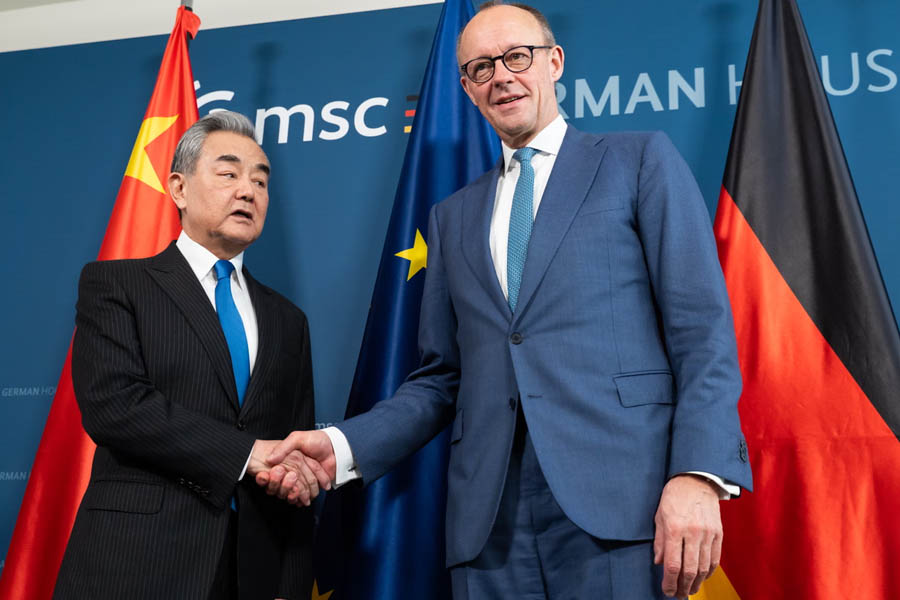Friedrich Merz shaking hands with Chinese Foreign Minister Wang Yi during a meeting at the Munich Security Conference amid rising China-Germany trade ties.