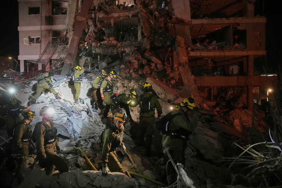 Israeli security forces inspect destroyed buildings that were hit by a missile fired from Iran, near Tel Aviv, Israel, Sunday, June 15, 2025.