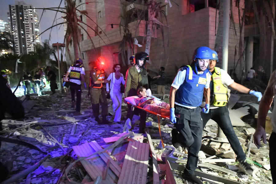 Israeli security and rescue forces evacuate a woman at the site of an Iranian missile attack in Petah Tikva.