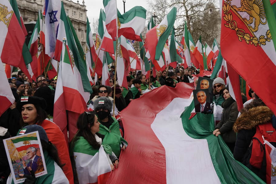 Protesters walking from Whitehall down central London streets toward the Iranian embassy, holding banners calling for regime change in Iran.