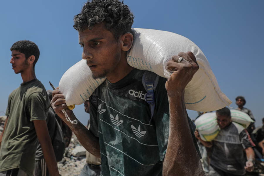 Internally displaced Palestinians carry bags of flour from a food distribution point in Zikim, northern Gaza.
