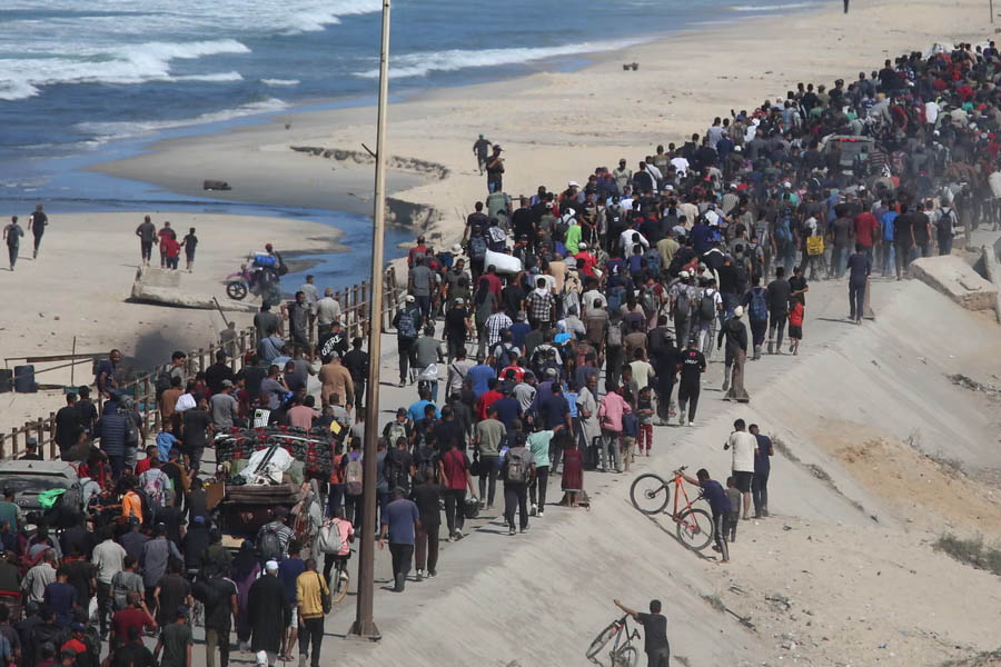 Palestinian families returning from southern Gaza to their homes in northern Gaza after being displaced by the recent war, carrying belongings and walking through damaged streets.