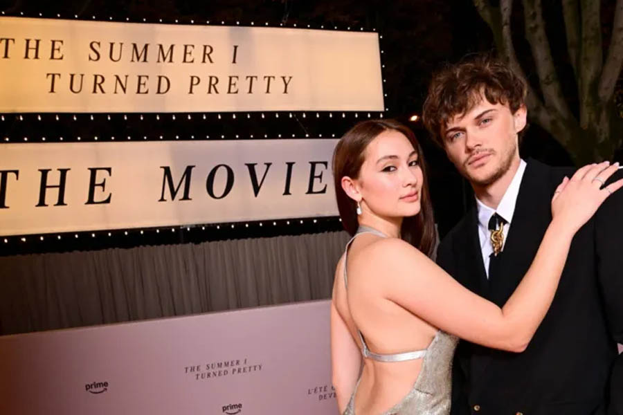 Lola Tung as Belly and Christopher Briney as Conrad pose on the red carpet in Paris in front of a billboard revealing The Summer I Turned Pretty will conclude with a feature film.